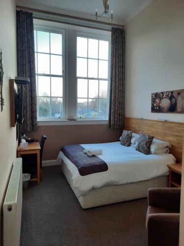 坎贝尔城Grammar Lodge Guest House的一间卧室设有一张床和两个窗户。