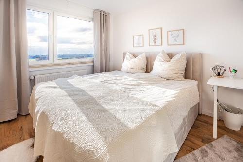 施泰恩巴赫陶努斯Moderne 2-Zimmer-Wohnung mit atemberaubender Skyline Aussicht auf Frankfurt!的白色卧室设有白色的床和窗户