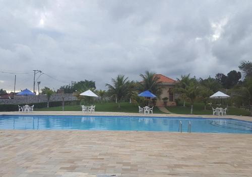 阿拉鲁阿马Recanto de Araruama的一个带白色椅子和遮阳伞的游泳池