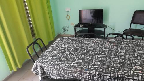 拉蓬塔La Trinidad San Luis, La Punta的一间卧室配有一张床、两把椅子和电视