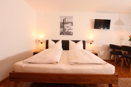 里茨勒恩亚希曼旅馆的一间卧室配有带白色床单和枕头的床。