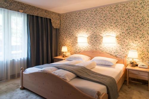 德弗雷根谷地圣雅各布阿尔卑霍夫酒店的一间卧室配有一张带花卉壁纸的大床