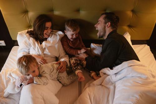 拉尔特Hotel Inn Salland的和孩子一起坐在床上的家庭