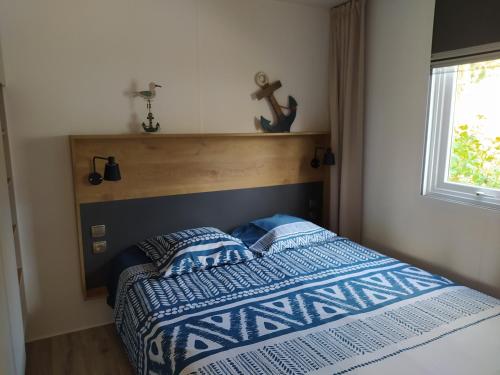 坎佩尔Mobile Home tout confort C13 Domaine de Lanniron的一间卧室配有一张带蓝色和白色棉被的床