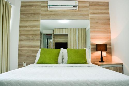 纳塔尔KING's FLAT HOTEL NATAL的卧室配有带绿色枕头的白色床