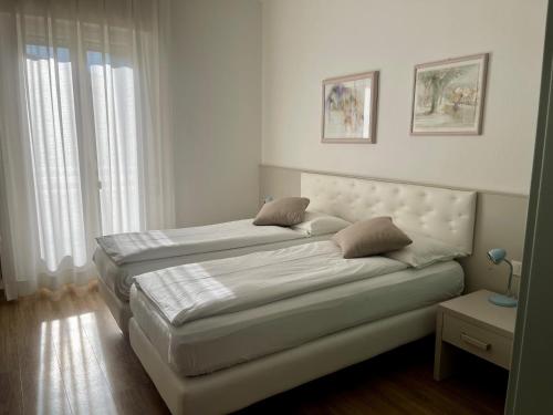 阿科Hotel Garden Arco的一间卧室设有两张床和两个窗户。