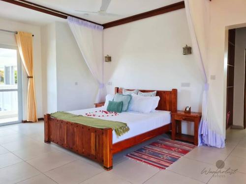 迪亚尼海滩Fiorella Beach House, Diani Beach的一间卧室设有一张大型木床和一个窗户。