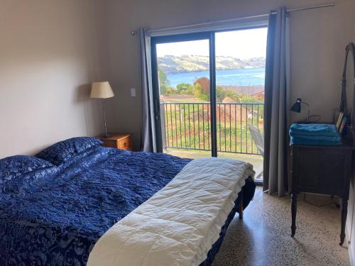 但尼丁Commanding Harbour views exquisite sunset vista的一间卧室设有一张床和一个美景阳台