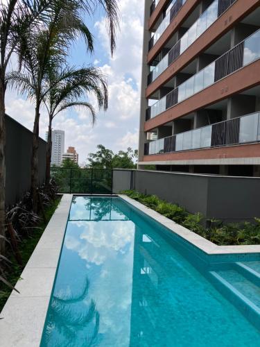圣保罗São Paulo - Vila Mariana - Central的棕榈树建筑前的游泳池