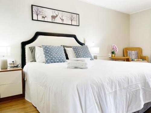 奥克兰Pupuke Manor Motel的一间卧室配有带白色床单和蓝色枕头的床。