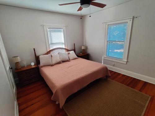 莱克兰Beautiful Mid Century Bungalow In The Heart of Lakeland的一间卧室配有一张带风扇的床和两个窗户。