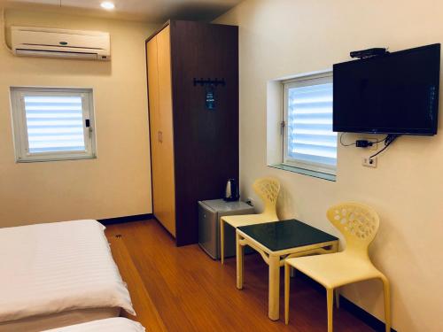 台南来七桃旅店的小房间设有一张床、一张桌子和两把椅子