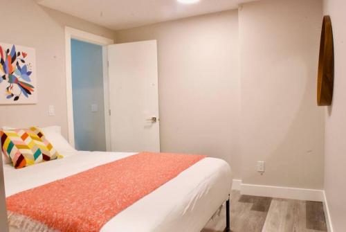 卡尔加里Modern 1br Home Full Kitchen Smarttv的白色卧室配有带橙色毯子的床