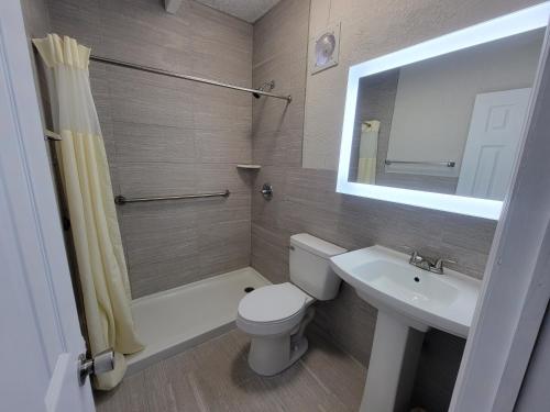 温特黑文Budget Inn Winter Haven Auburndale的一间带卫生间、水槽和镜子的浴室