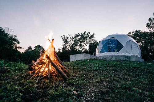 LuboFamily Dome Glamping in Rizal with Private Hotspring的 ⁇ 火旁的草原上的一个帐篷和火