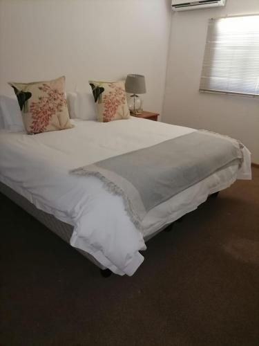 Prince Alfreds HamletRooikraal Welgeluk cottage的卧室配有一张带白色床单和枕头的大床。