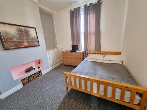 普雷斯顿Cheerful 4 bedroom close to Uclan, Preston City Center的一间卧室设有一张木床和一个窗户。