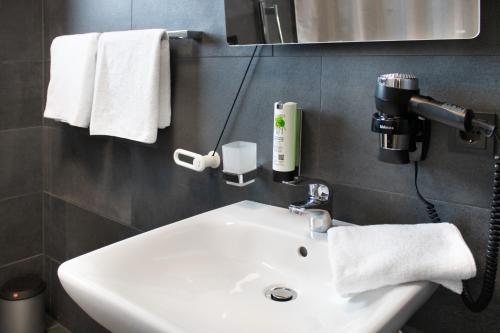 因戈尔施塔特ING Hotel by WMM Hotels的浴室设有白色水槽、镜子和毛巾