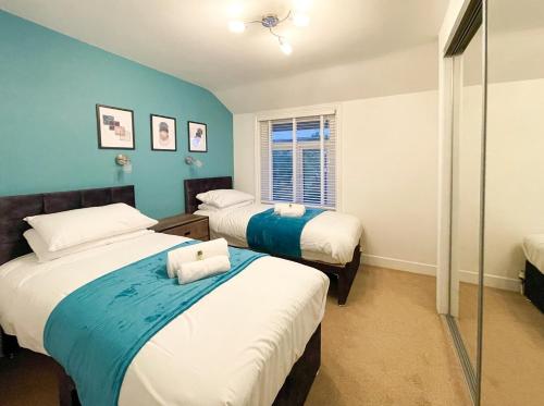史云顿SHRIVENHAM - Spacious Home, High Speed Wi-Fi, Free Parking, Garden的蓝色墙壁客房的两张床