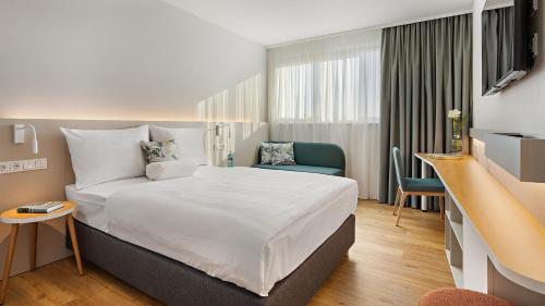 卡尔斯鲁厄Styles Hotel Karlsruhe Messe的酒店客房设有一张大床和一张书桌。