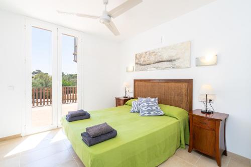 马纳科尔Apartament Cala Anguila的一间带绿色床的卧室和一个阳台