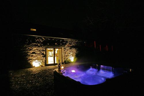 普里茅斯Sunridge Fishing Lodge with Hot Tub & Giant Cinema的夜间在大楼前的热水浴池