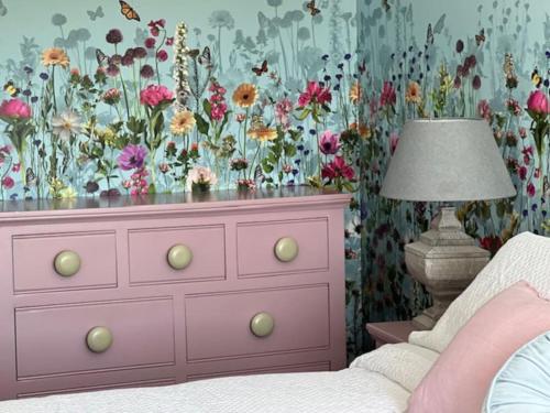 莫法特Cosy country cottage in rural location的卧室配有粉红色梳妆台和花卉壁纸