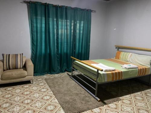 班珠尔Fajara Suites, Bakau, Banjul, Gambia的一间卧室配有床和绿帘