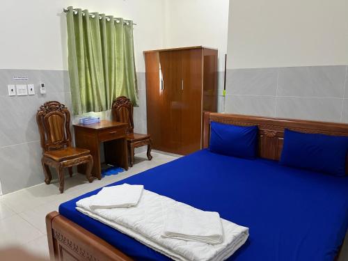 Lai VungKhách sạn Hoàng Gia - TT Lai Vung的一间卧室配有一张蓝色的床、一张桌子和椅子