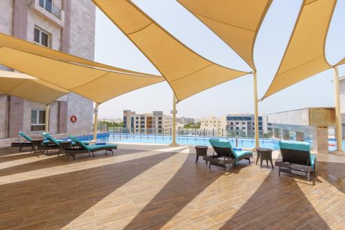 马斯喀特Levatio Suites Muscat, a member of Radisson Individuals的一个带黄色遮阳伞和椅子的庭院和一个游泳池