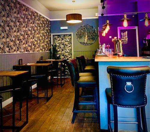 杰德堡The Capon Tree Town House的餐厅内带黑色椅子和紫色墙壁的酒吧