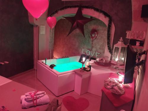韦列Afrodite Luxury Suite的粉红色的房间,配有带爱情标志的浴缸
