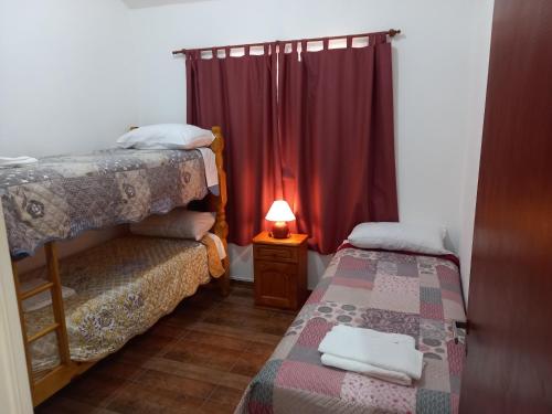 梅洛El Piscui House的小房间设有两张床和一盏灯