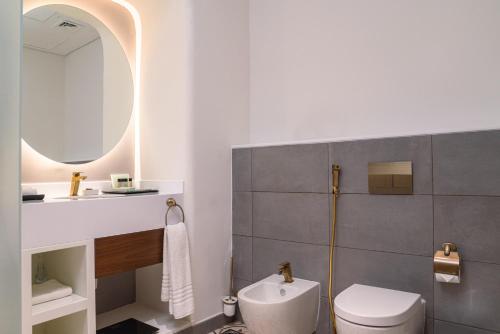 多哈Mina Hotel and Residences的一间带卫生间、水槽和镜子的浴室