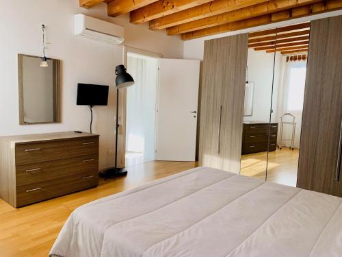 罗维戈Appartamento Donà的一间卧室配有一张床、梳妆台和镜子