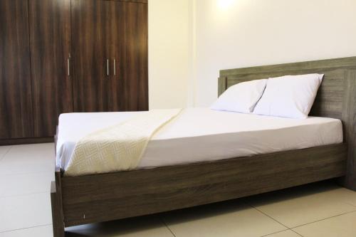 MatolaMatola View Residence的一间卧室配有一张带白色床单和枕头的木制床。