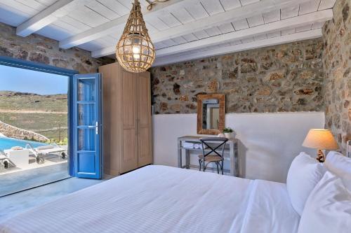 帕诺尔莫斯米科诺斯Elegant Mykonos Villa Air Private Pool 4 Bedrooms Sea View Panormos的一间卧室配有一张床、一张桌子和一个窗户。
