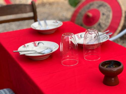 南邦กิ่วลม - ชมลคอร Kiwlom - Chomlakorn, Lampang, TH的红色桌布上带板子和玻璃杯的红色桌