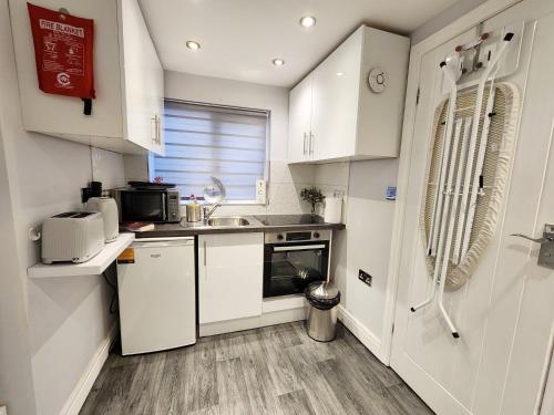 科恩布鲁克Studio Apartment The Den Colnbrook的小厨房配有白色橱柜和水槽