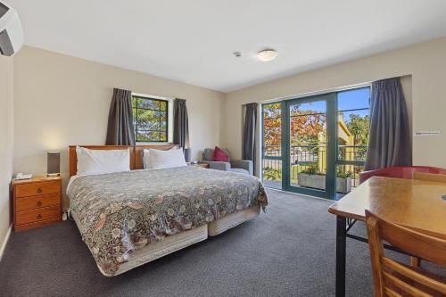 基督城Denton Park Motel的一间卧室配有一张床、一张书桌和一个窗户。