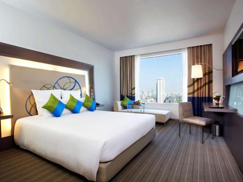 曼谷Novotel Bangkok Ploenchit Sukhumvit的一间酒店客房,设有一张大床和一个大窗户