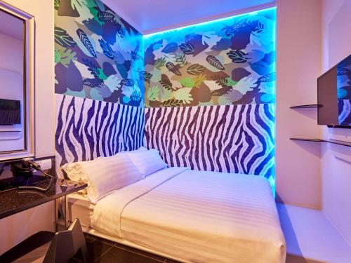 新加坡ibis budget Singapore Bugis的一间卧室配有一张蓝色的灯光床