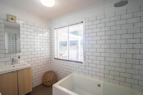 波因特卢考特Palm Beach House - sleeps 10 - spacious的白色的浴室设有浴缸和水槽。