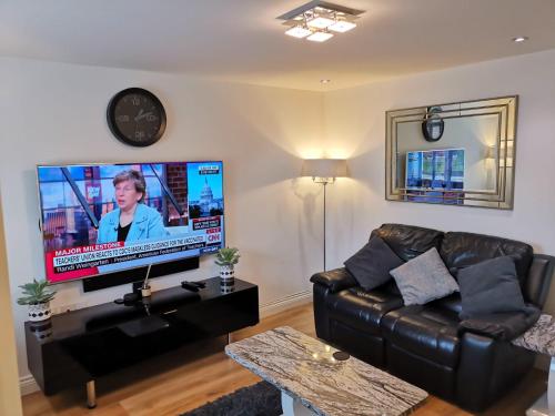 KentLangley Haven - 3 BR House的客厅配有黑色真皮沙发和平面电视。