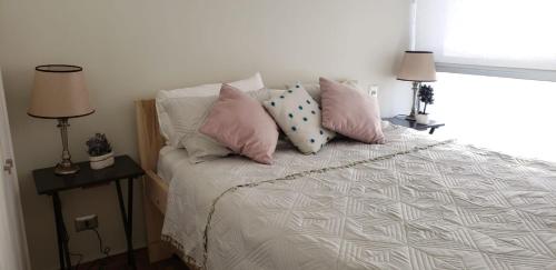 康康Departamento en Bosques de Montemar的一间卧室配有带粉色和白色枕头的床