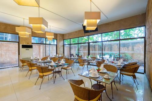 芭堤雅市中心贝拉别墅普瑞玛酒店的餐厅设有桌椅和大窗户。