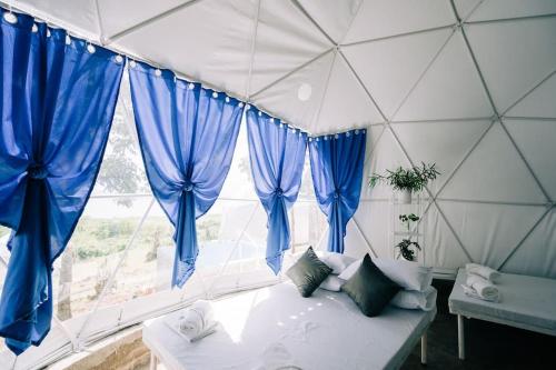 LuboGroup Dome Glamping with Private Hotspring的客房设有带蓝色窗帘的床和窗户。