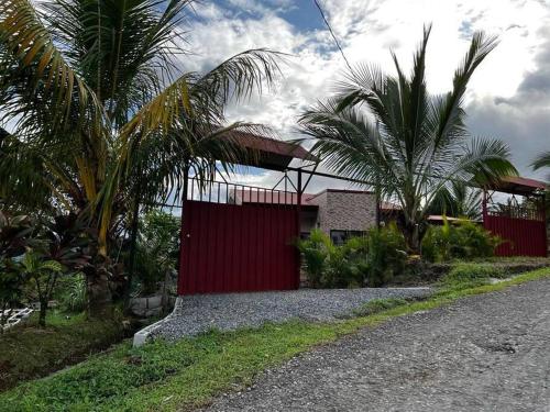 福尔图纳Villas Altos del Arenal的一座红色围栏和棕榈树的房子
