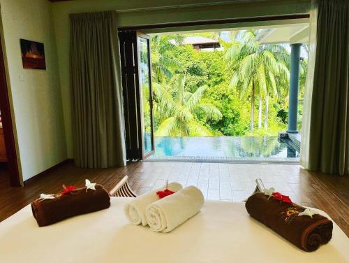 马埃岛贝拉扎尔区Anse Soleil Beachcomber Hotel and Self Catering的床上的三条毛巾,享有泳池美景