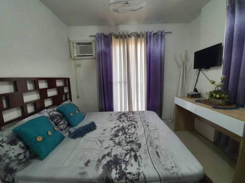 CaintaCozy Place 2BR Condo Unit in Ortigas Ave Ext的一间卧室配有一张带蓝色枕头的大床